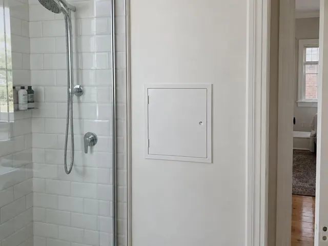 Small access panel on a bathroom wall beside a tiled shower in a home in Tempe